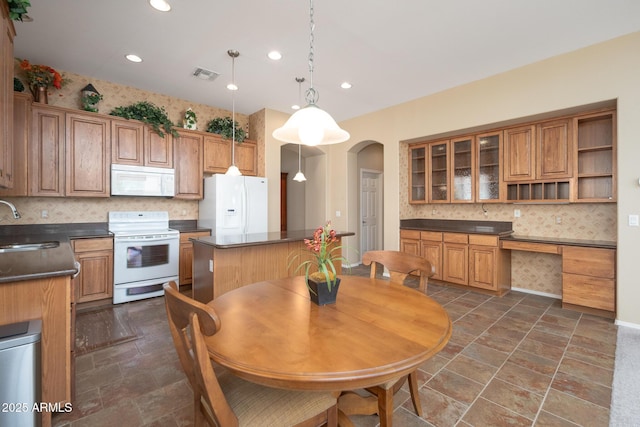 kitchen featuring dark countertops, visible vents, backsplash, arched walkways, and white appliances