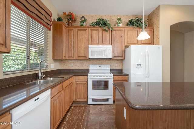 kitchen featuring white appliances, dark stone countertops, arched walkways, a sink, and hanging light fixtures