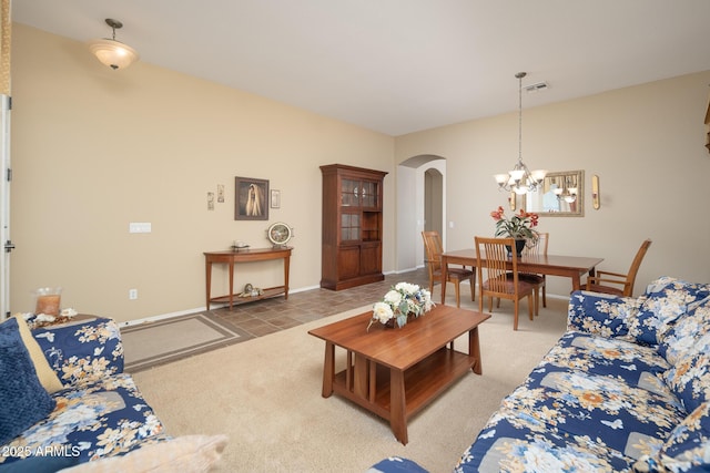 living room featuring arched walkways, visible vents, light carpet, and a chandelier