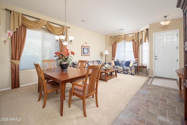 carpeted dining space featuring visible vents, baseboards, and a chandelier