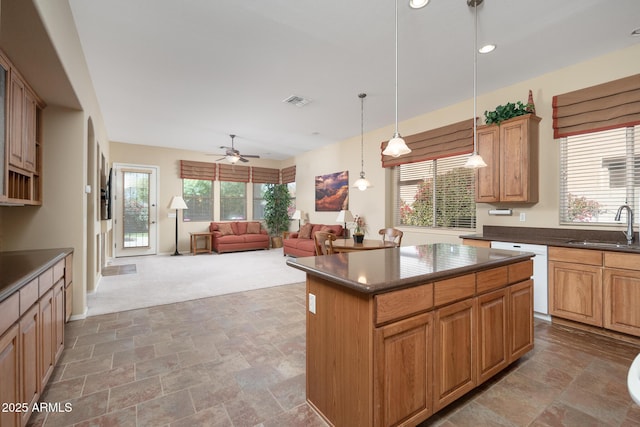 kitchen with visible vents, a sink, stone finish flooring, a kitchen island, and dark countertops