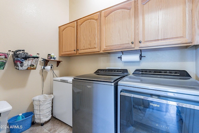 washroom featuring cabinets, washing machine and dryer, and light tile patterned flooring