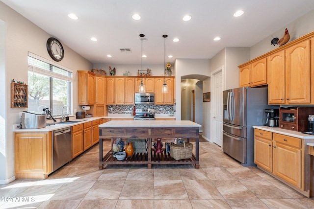 kitchen with hanging light fixtures, sink, a kitchen island, appliances with stainless steel finishes, and decorative backsplash