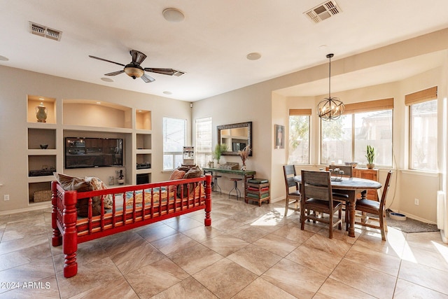 dining space with ceiling fan with notable chandelier, built in shelves, and plenty of natural light