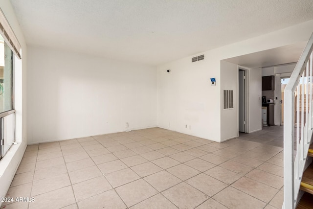 tiled empty room with a textured ceiling