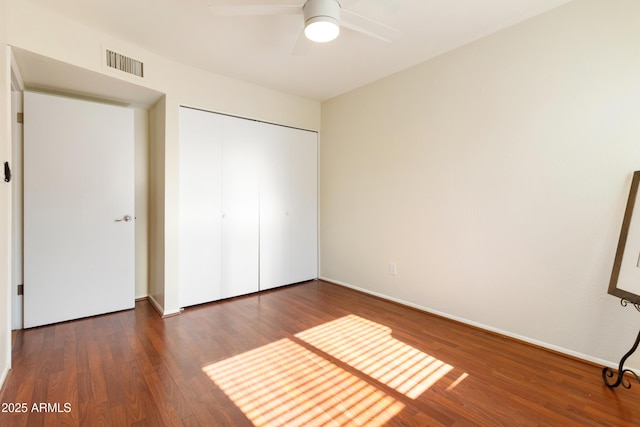 unfurnished bedroom featuring a closet, dark hardwood / wood-style flooring, and ceiling fan