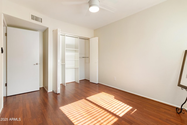 unfurnished bedroom with dark wood-type flooring, a closet, and ceiling fan