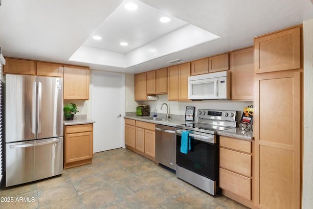 kitchen featuring light brown cabinetry, sink, a tray ceiling, and stainless steel appliances