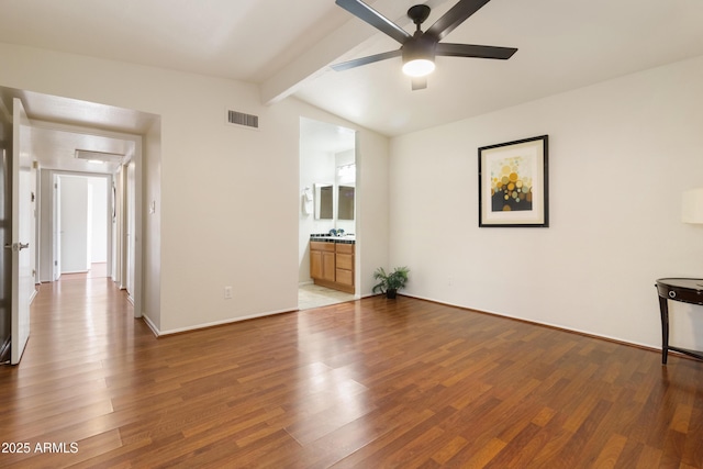 unfurnished living room featuring ceiling fan, wood-type flooring, and vaulted ceiling with beams