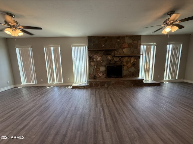 unfurnished living room with dark wood finished floors, baseboards, and a ceiling fan