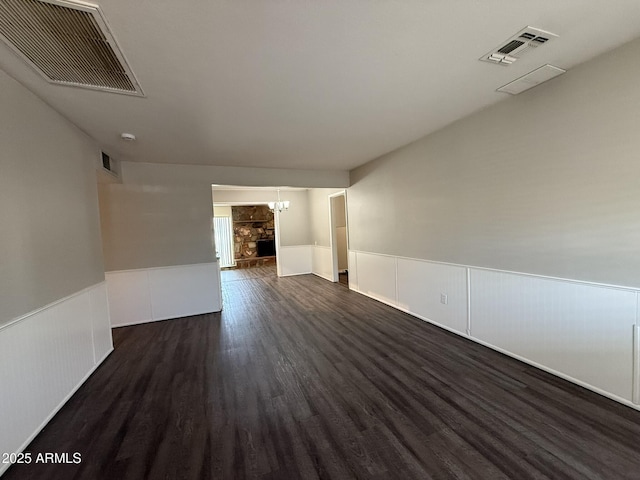 spare room with dark wood-style flooring, a wainscoted wall, and visible vents