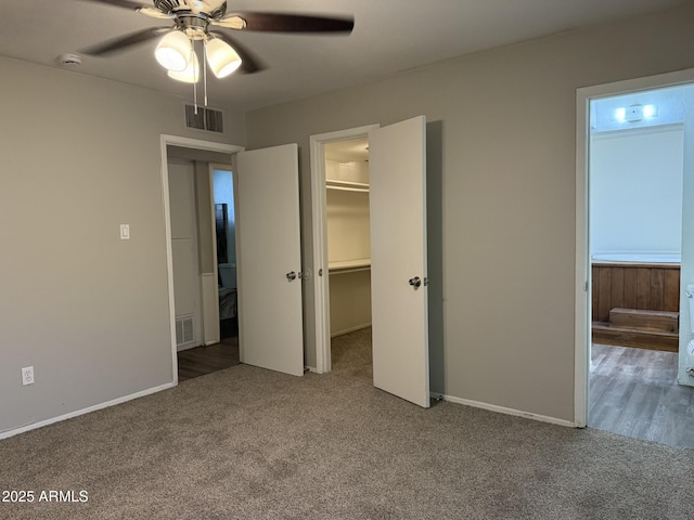 unfurnished bedroom featuring a ceiling fan, visible vents, carpet floors, and a walk in closet