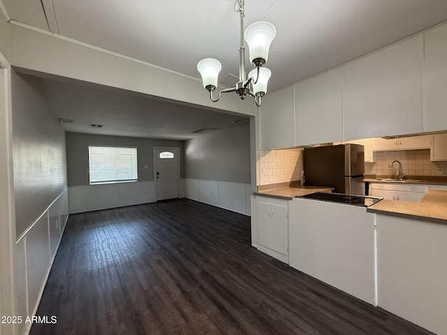 kitchen with a sink, black electric stovetop, freestanding refrigerator, dark wood-style floors, and white cabinets