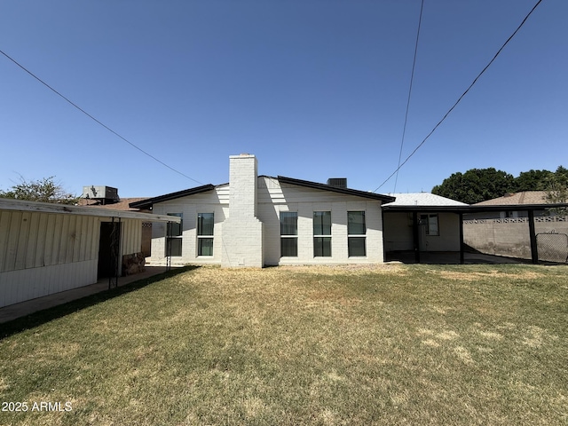 back of property featuring a yard, a chimney, and fence