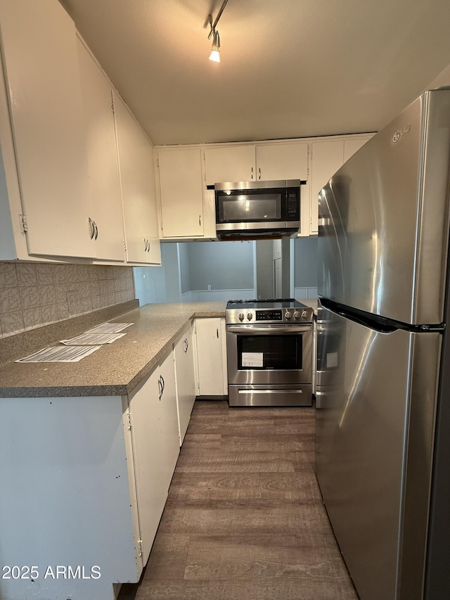 kitchen featuring white cabinets, appliances with stainless steel finishes, dark wood-type flooring, and decorative backsplash