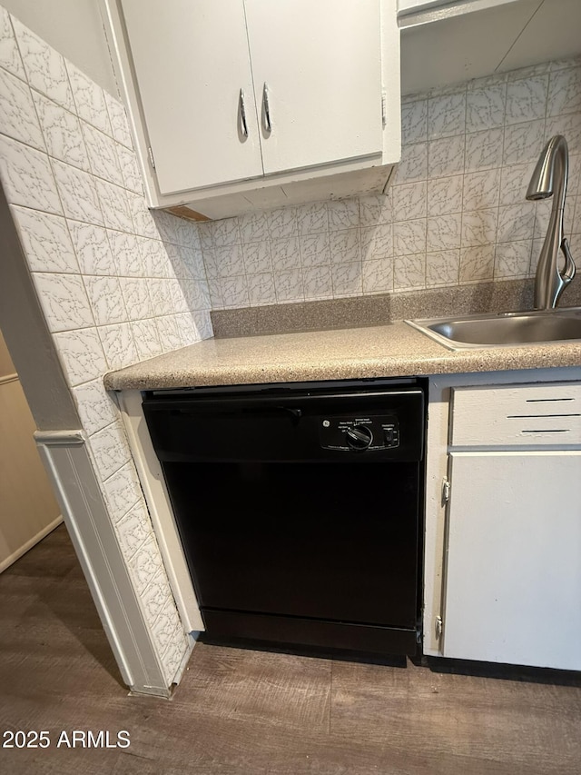 interior details with a sink, black dishwasher, white cabinets, backsplash, and light countertops