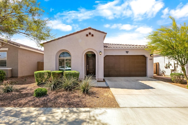 mediterranean / spanish-style home with a tiled roof, driveway, a garage, and stucco siding