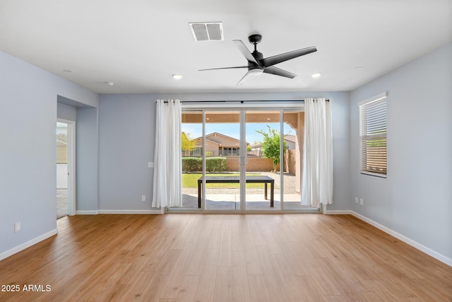spare room with light wood-type flooring, baseboards, a ceiling fan, and visible vents