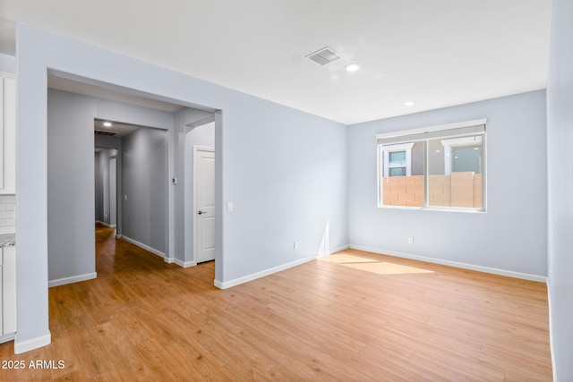 empty room featuring light wood-style floors, baseboards, and visible vents