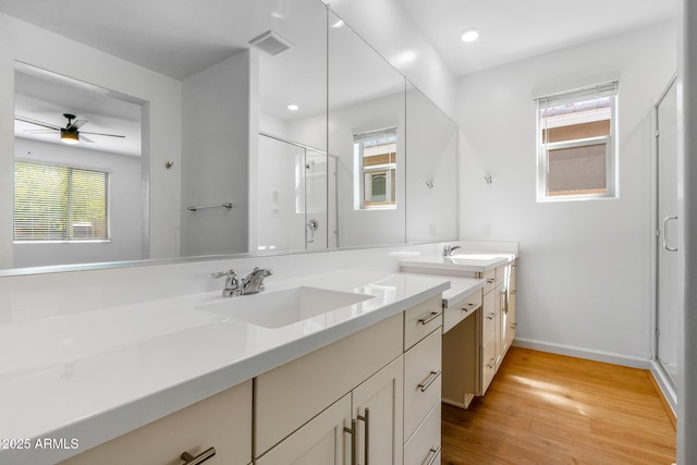bathroom featuring a stall shower, plenty of natural light, visible vents, a sink, and wood finished floors