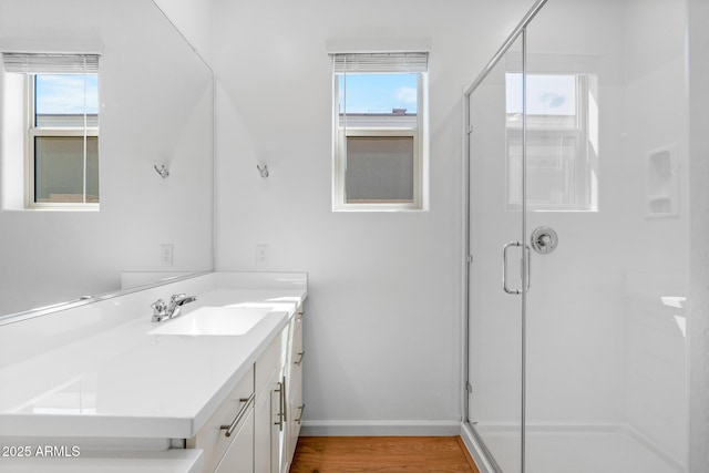 bathroom featuring a stall shower, a healthy amount of sunlight, wood finished floors, and vanity