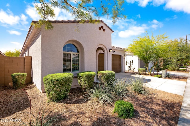 mediterranean / spanish home featuring a tiled roof, driveway, stucco siding, and a garage