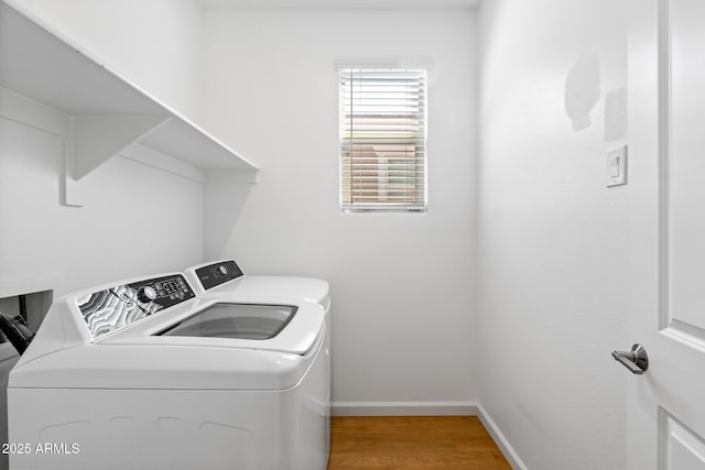 laundry area featuring washer and clothes dryer, light wood finished floors, laundry area, and baseboards