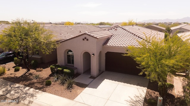 mediterranean / spanish-style house with stucco siding, driveway, a garage, and a tile roof