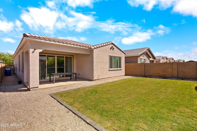 rear view of house featuring a patio, stucco siding, a fenced backyard, a yard, and a tiled roof