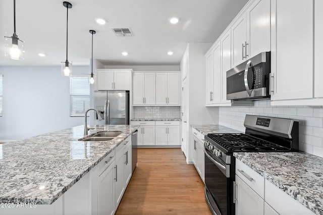 kitchen featuring light wood-type flooring, white cabinets, visible vents, appliances with stainless steel finishes, and a sink
