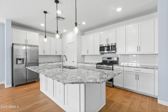 kitchen featuring light wood-style flooring, white cabinetry, visible vents, appliances with stainless steel finishes, and a sink