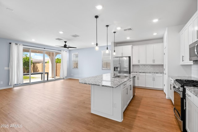 kitchen featuring visible vents, a sink, a ceiling fan, stainless steel appliances, and backsplash