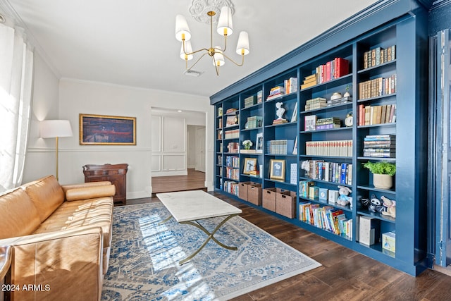 sitting room featuring dark wood-type flooring, ornamental molding, and an inviting chandelier