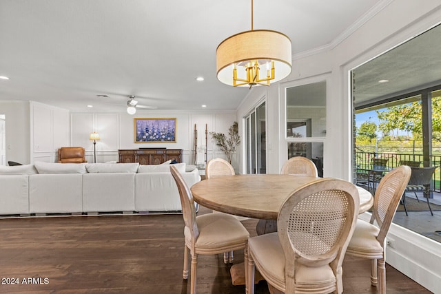 dining space with ornamental molding, dark wood-type flooring, and ceiling fan with notable chandelier