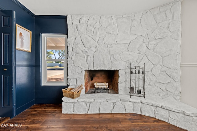 room details featuring a stone fireplace, ornamental molding, and hardwood / wood-style floors