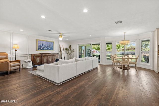 living room featuring ceiling fan, a healthy amount of sunlight, dark hardwood / wood-style flooring, and crown molding