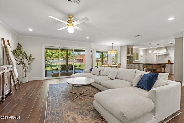 living room featuring crown molding, sink, dark wood-type flooring, and ceiling fan