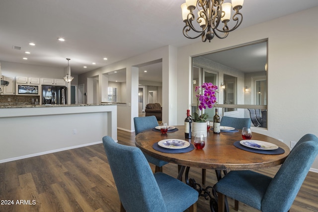 dining space with dark hardwood / wood-style flooring and an inviting chandelier