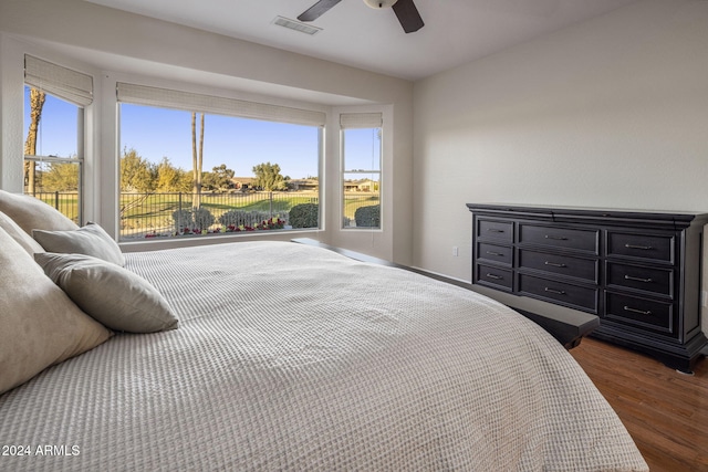 bedroom featuring ceiling fan, dark hardwood / wood-style flooring, and multiple windows