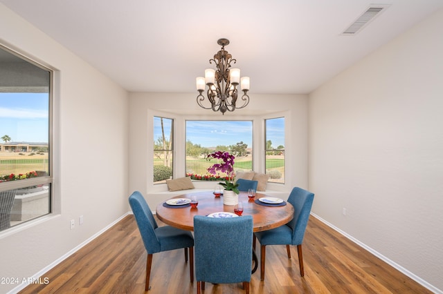 dining space featuring hardwood / wood-style flooring and an inviting chandelier