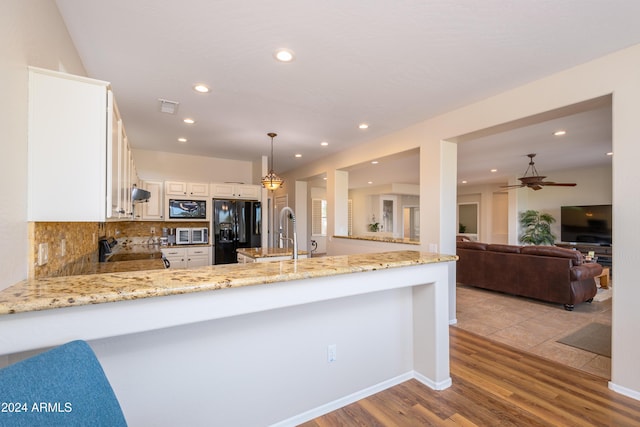 kitchen featuring sink, backsplash, kitchen peninsula, decorative light fixtures, and black appliances