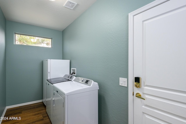 clothes washing area with separate washer and dryer and dark wood-type flooring