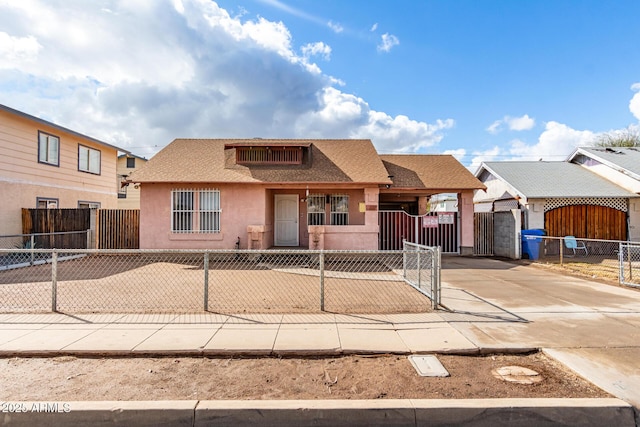 view of front facade with stucco siding, a fenced front yard, driveway, and a gate