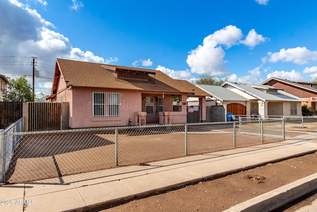 view of front of property featuring stucco siding, a fenced front yard, driveway, and a gate