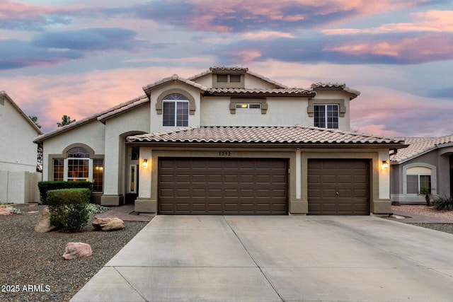 mediterranean / spanish-style home with stucco siding, concrete driveway, and a tile roof