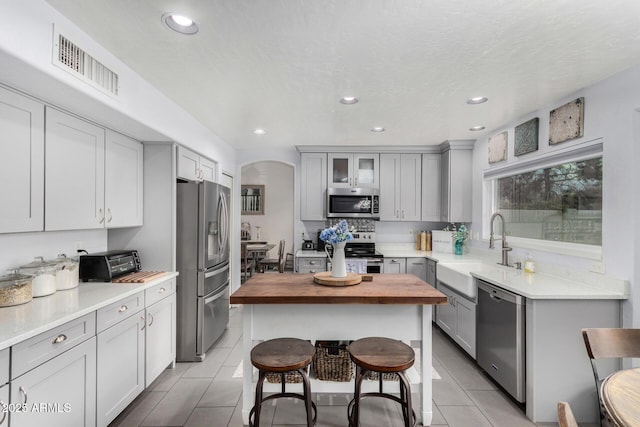 kitchen featuring visible vents, butcher block counters, light tile patterned floors, appliances with stainless steel finishes, and a sink