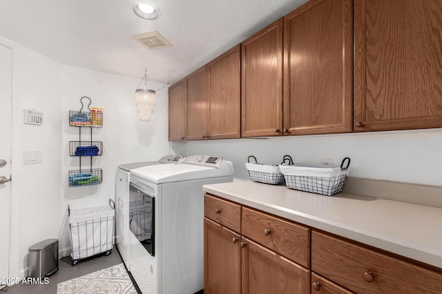 laundry area featuring tile patterned flooring, washing machine and dryer, cabinet space, and visible vents