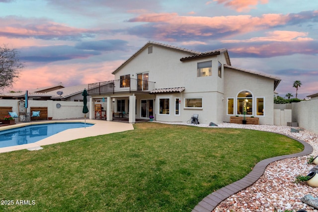 back of property featuring a balcony, a yard, a fenced backyard, stucco siding, and a patio area