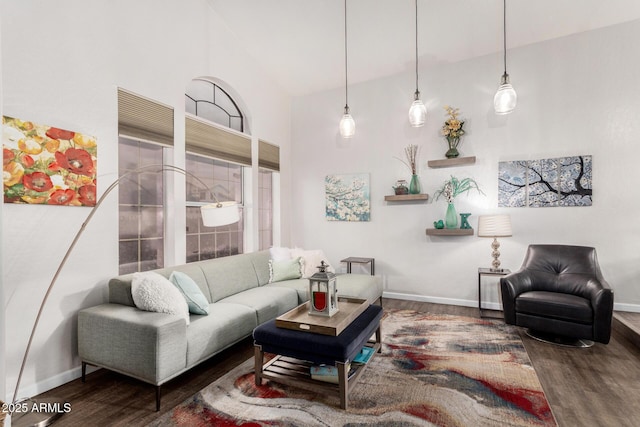 living area with baseboards, high vaulted ceiling, and wood finished floors