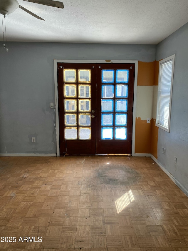 spare room featuring baseboards, a textured ceiling, and french doors